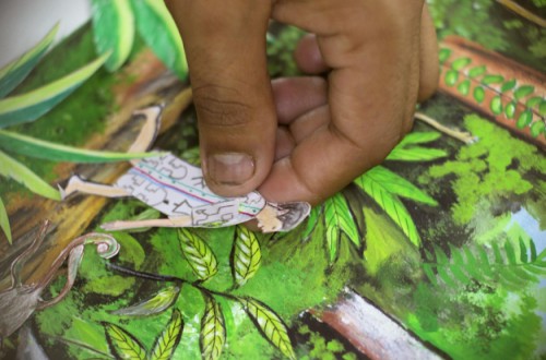 A student moves a drawn figure on an animated background of a rainforest